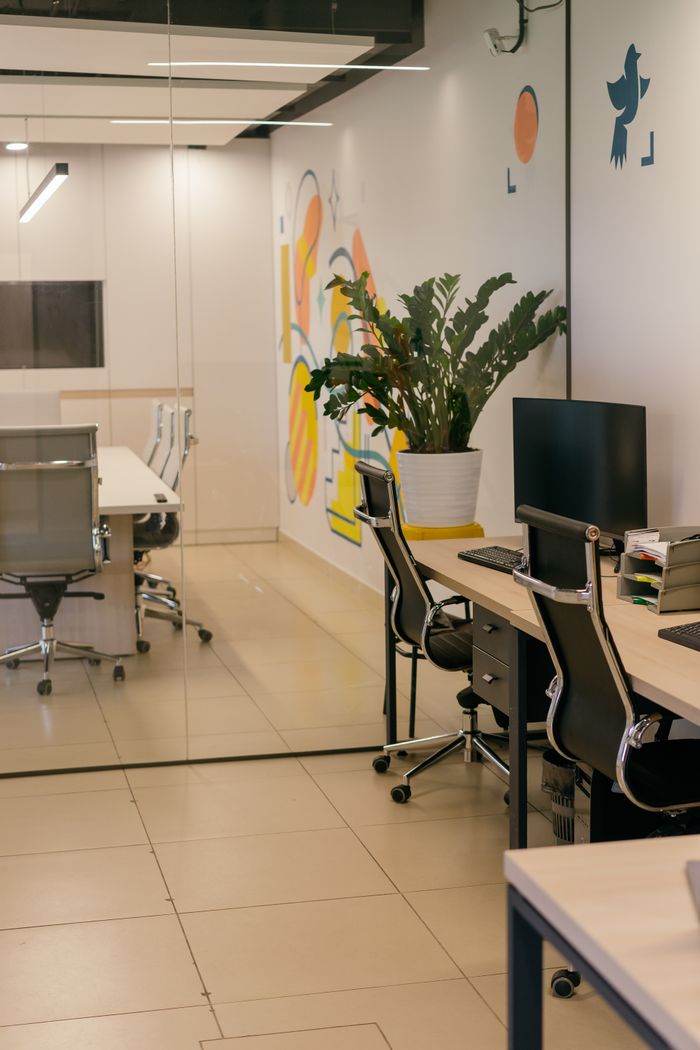 Interior de bureau spacieux et contemporain avec cloisons vitrées, mobilier élégant et œuvres murales éclatantes.